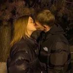 A couple is kissing under a tree.