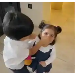 The boy is covering the girl's mouth.